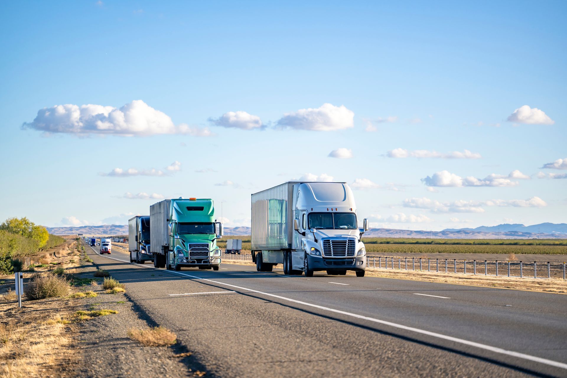 A group of semi trucks are driving down a highway.
