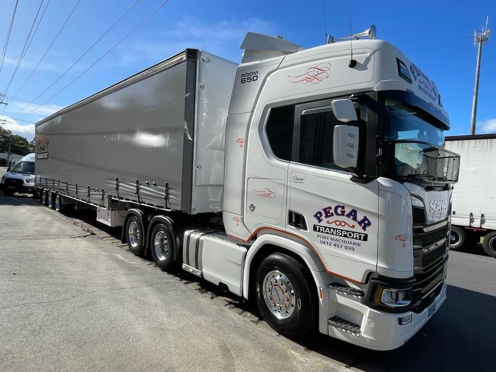 A Row Of White Trucks Are Parked In Front Of A Large White Building — Pegar Transport In Sydney, NSW
