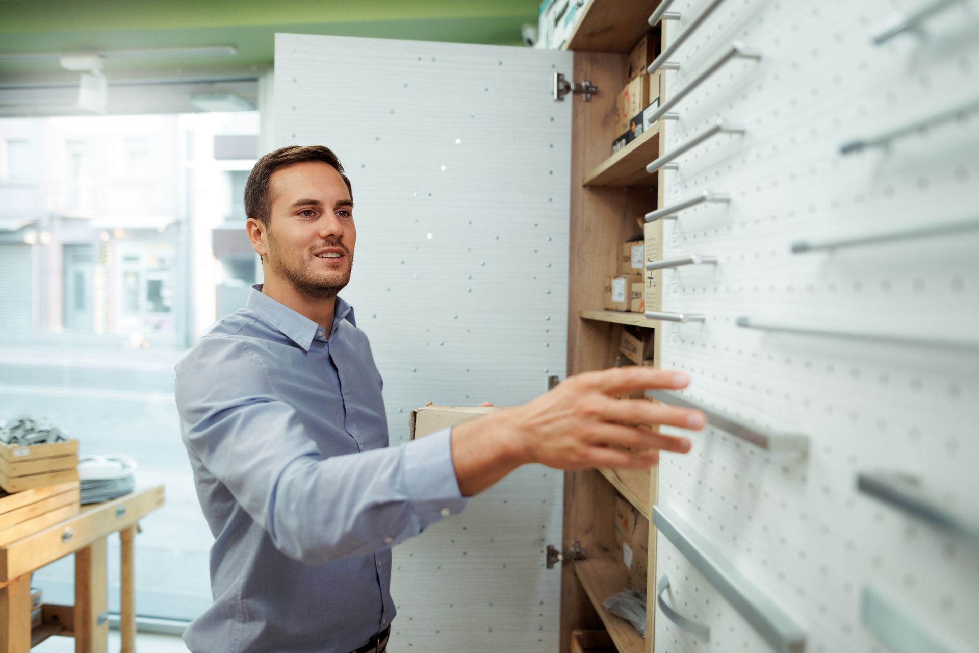 A man is looking at cabinet handles in a store. Man in a shirt looking at cabinet handles in a hardware store.