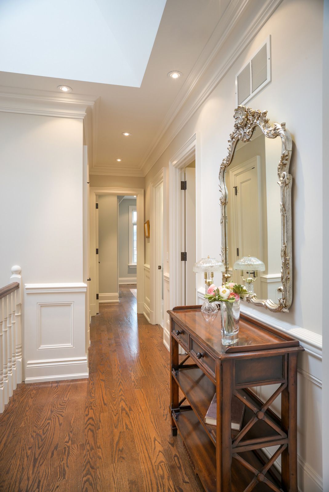 A hallway with a table and a mirror on the wall.