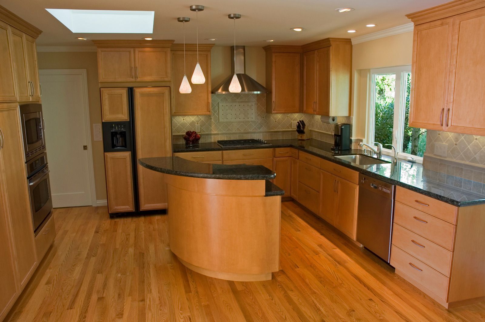 Spacious kitchen with wood cabinets, black countertops, and a curved island.