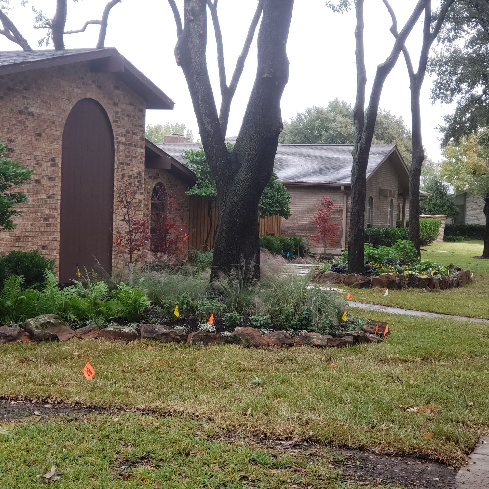 Houses with brown brick exteriors and lush landscaping on a cloudy day.