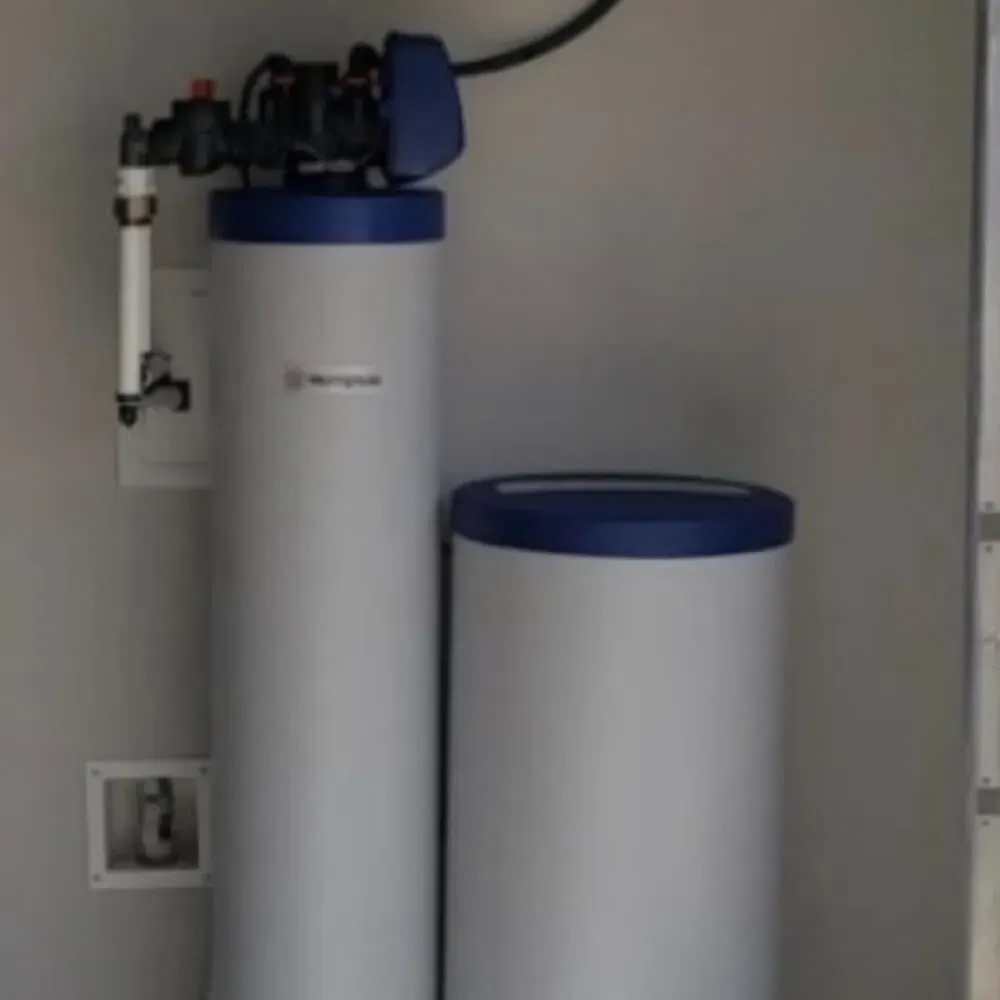 Two water softener tanks with blue lids and attached plumbing in a utility room