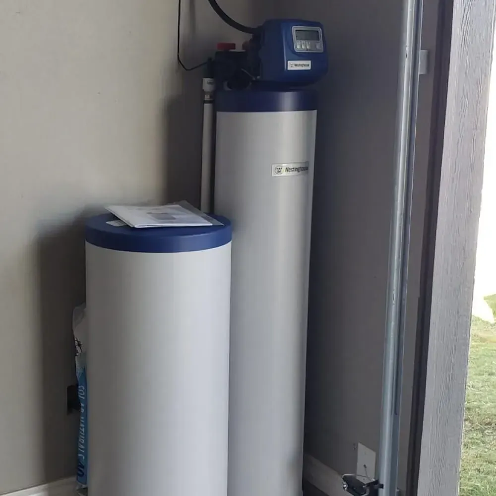 Two white and blue water softener tanks in a garage or utility room.