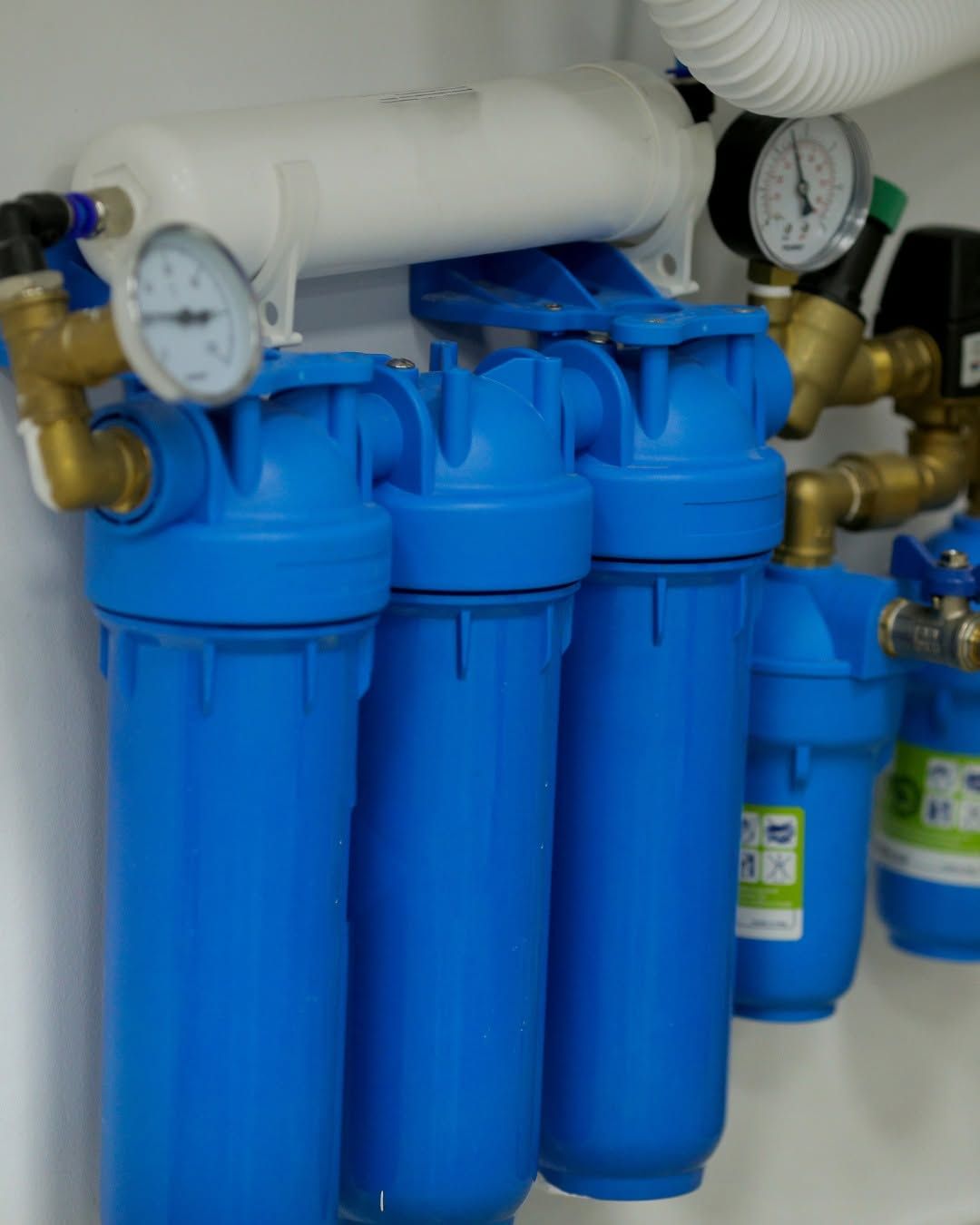 Blue water filtration system with pressure gauges and pipes in a utility area