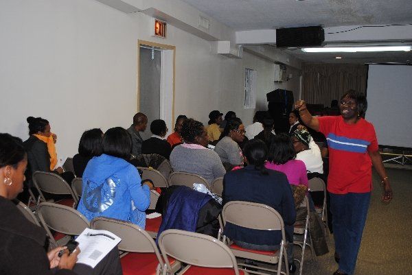 Eastchester Church of God. man in a red shirt stands in front of a group of people sitting in folding chairs