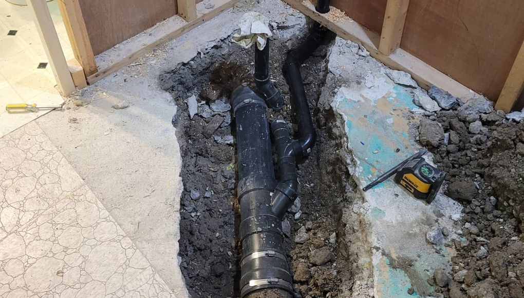 A person uses a thermal imaging camera under a sink to detect water leaks in plumbing.