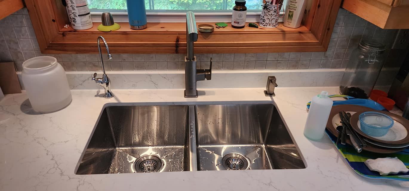 A kitchen sink with a double basin and faucet, with dirty dishes on the right.