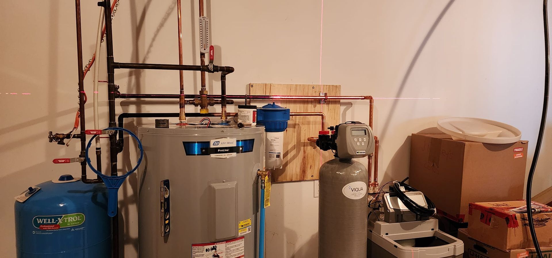 Water heater and related plumbing in a utility room; pipes, tanks, and electrical components.
