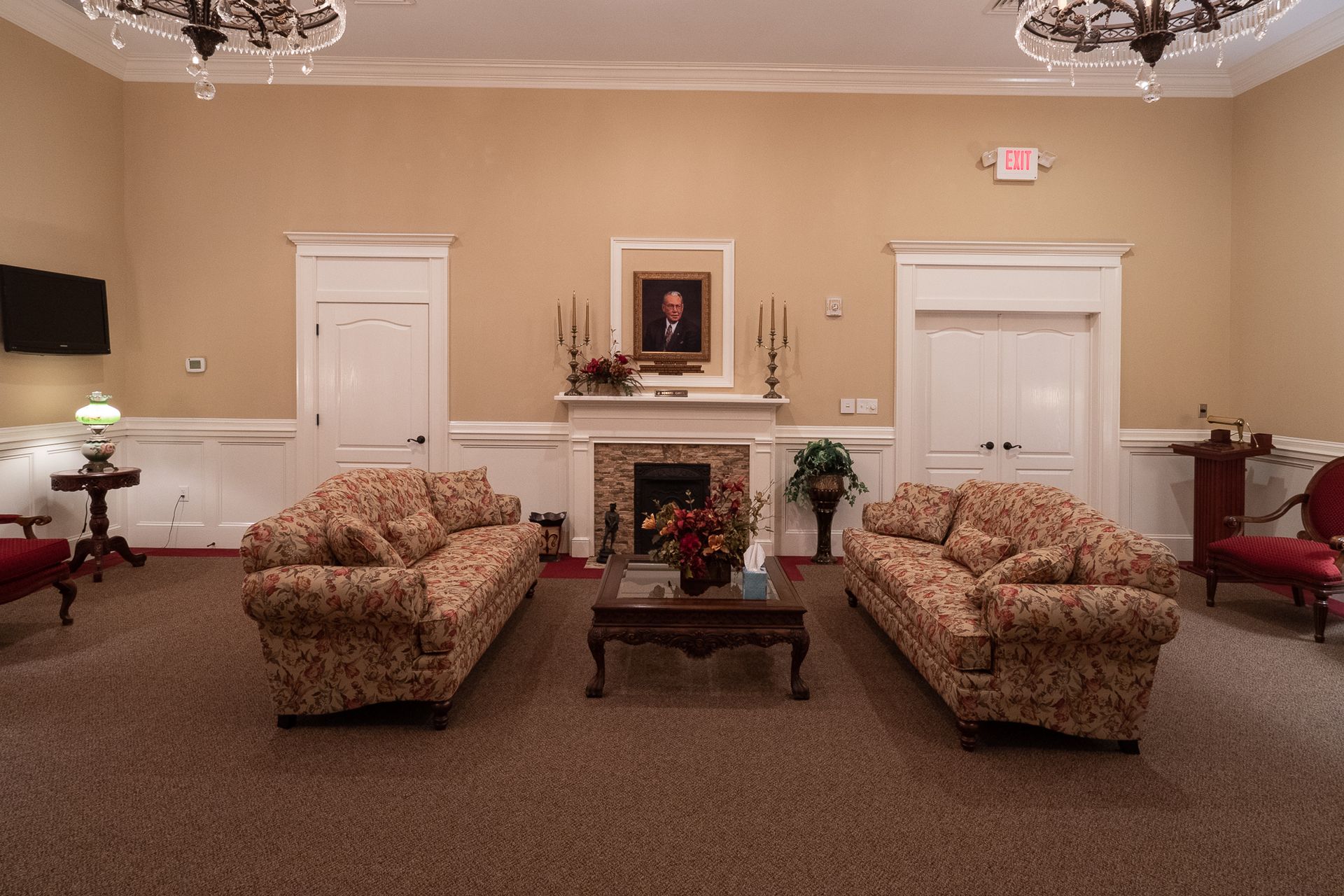 Elegant beige sitting room with floral sofas, fireplace, and white doors under chandeliers