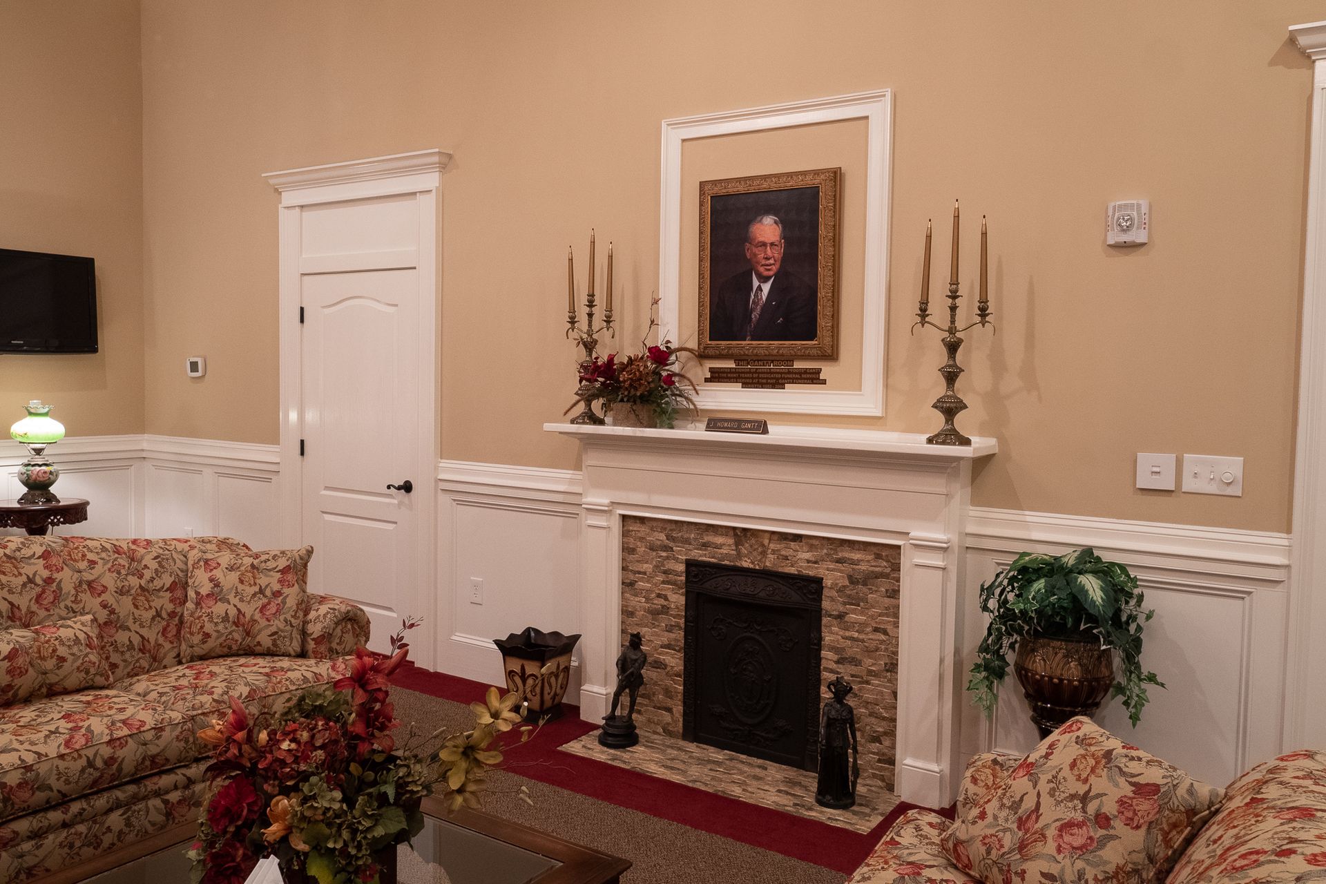 Elegant living room with fireplace, floral sofas, and framed portrait above mantel