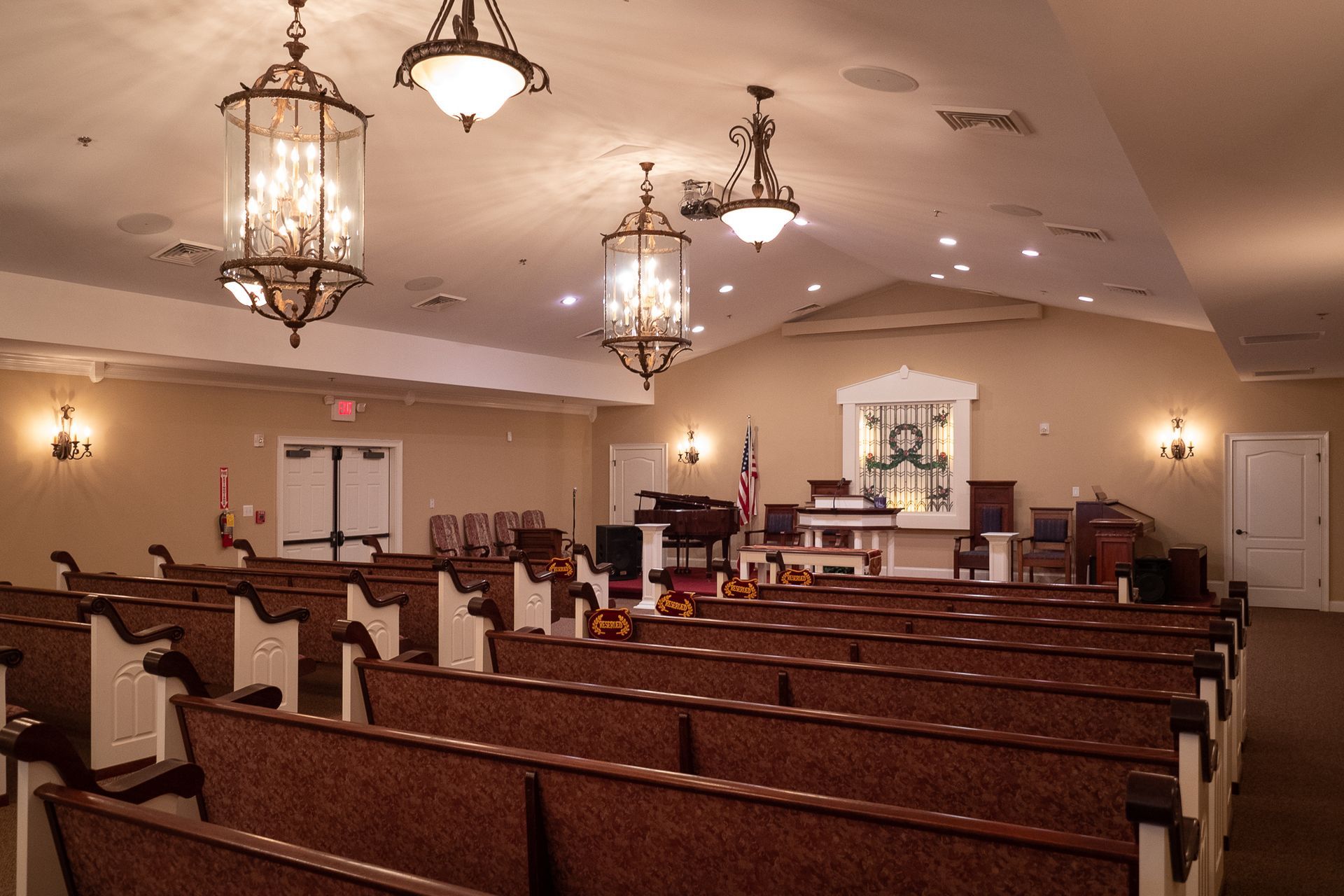 Empty church sanctuary with wooden pews, hanging chandeliers, and a dais at the front