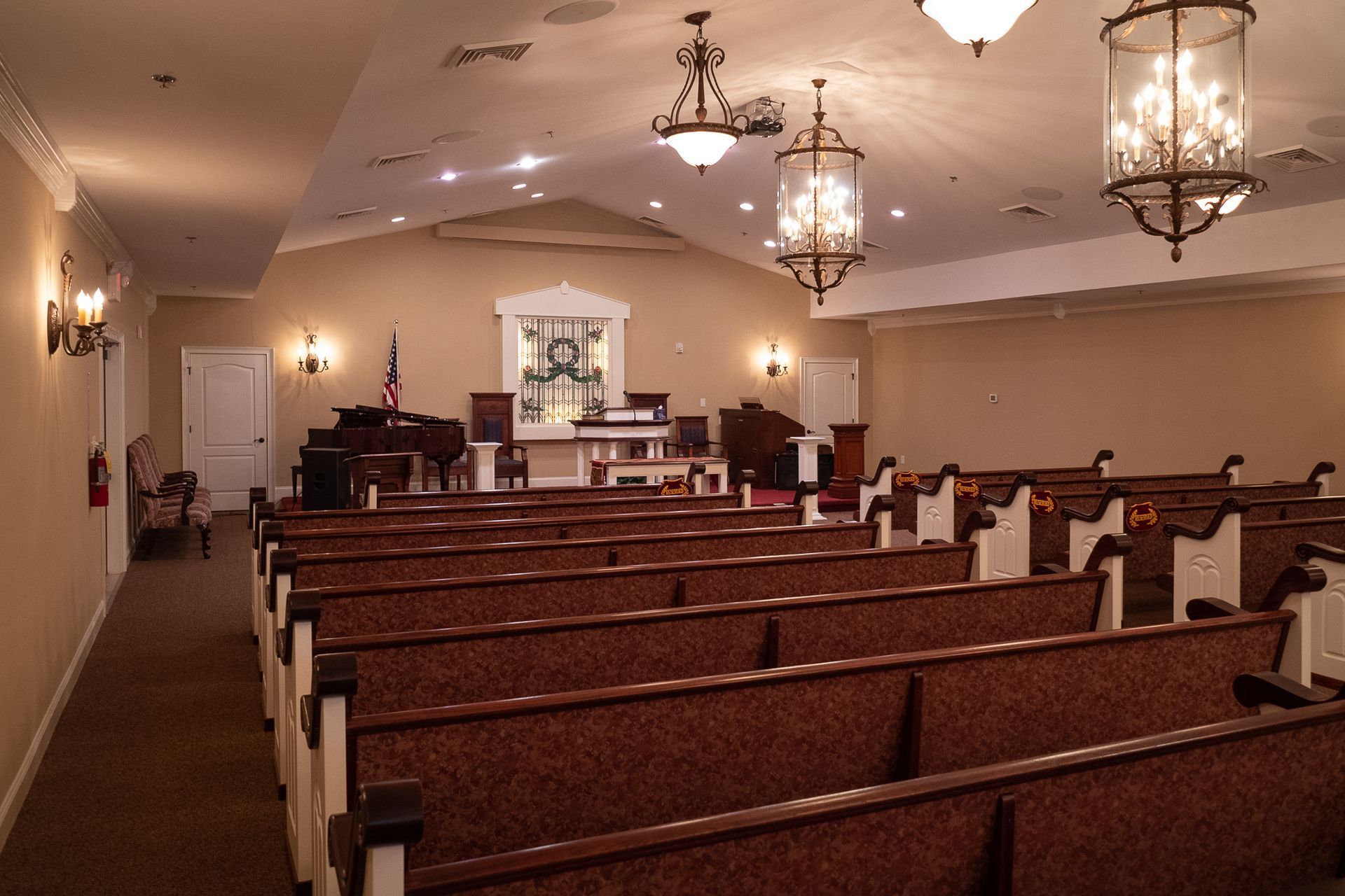 Empty church sanctuary with wooden pews, chandeliers, and an altar at the front