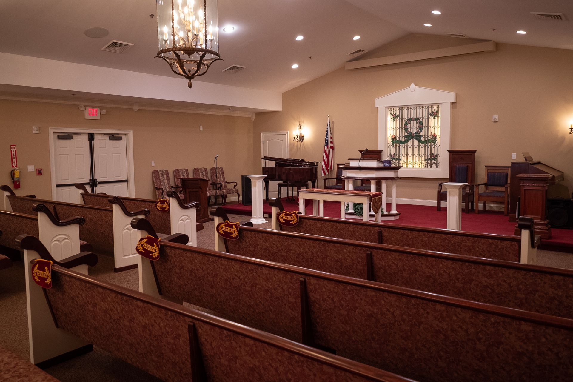 Empty church sanctuary with wooden pews, chandelier, and altar at the front