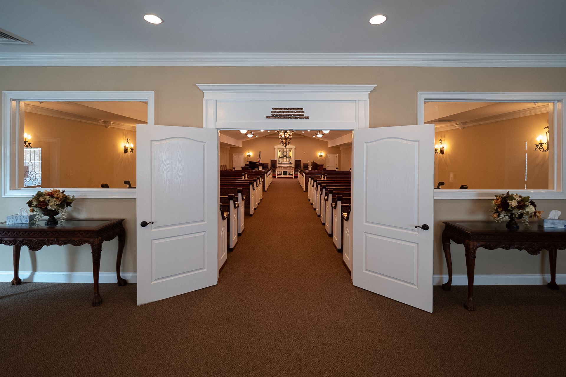 Open double doors to a banquet hall with long rows of white-draped chairs and tables