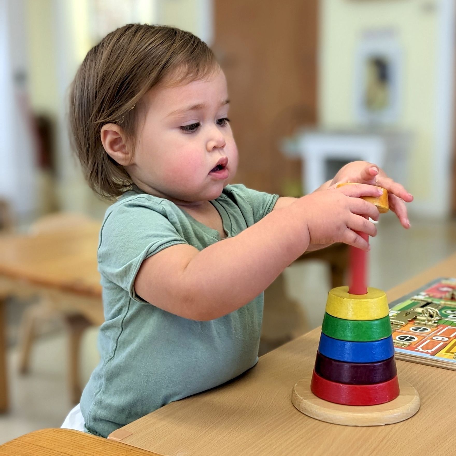 A Montessori little girl is playing with a wooden stacking toy