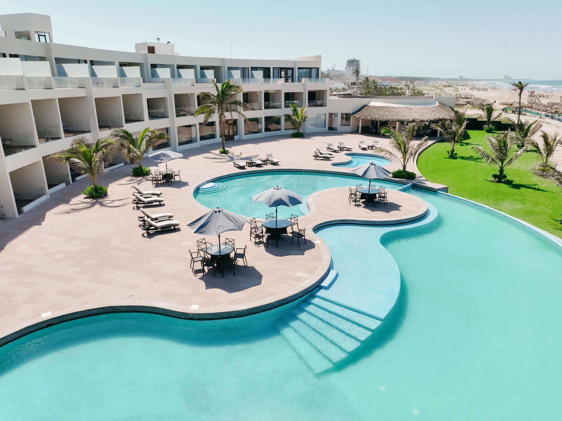 An aerial view of a large swimming pool in front of a hotel