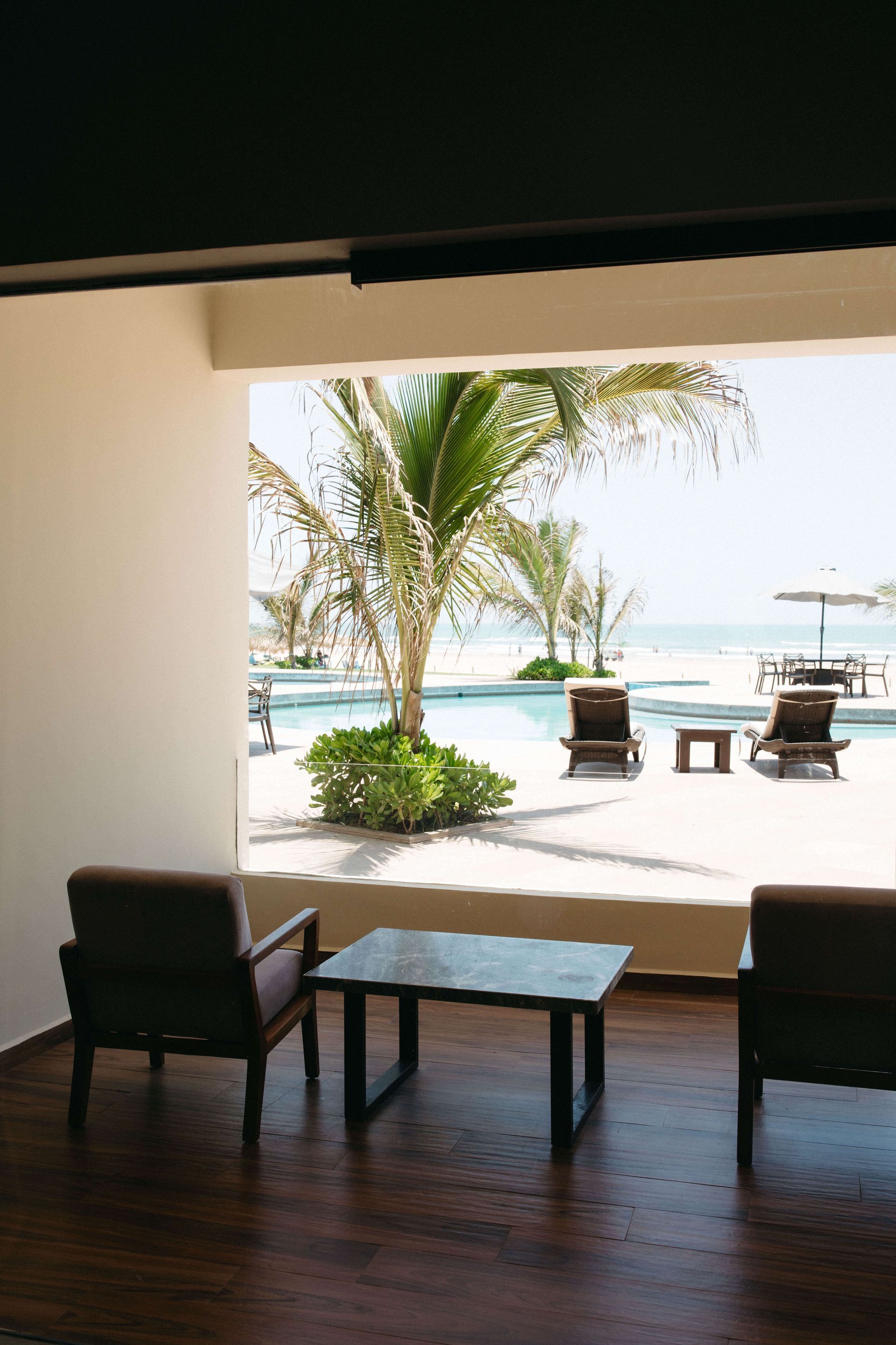 A room with two chairs and a table with a view of a swimming pool.