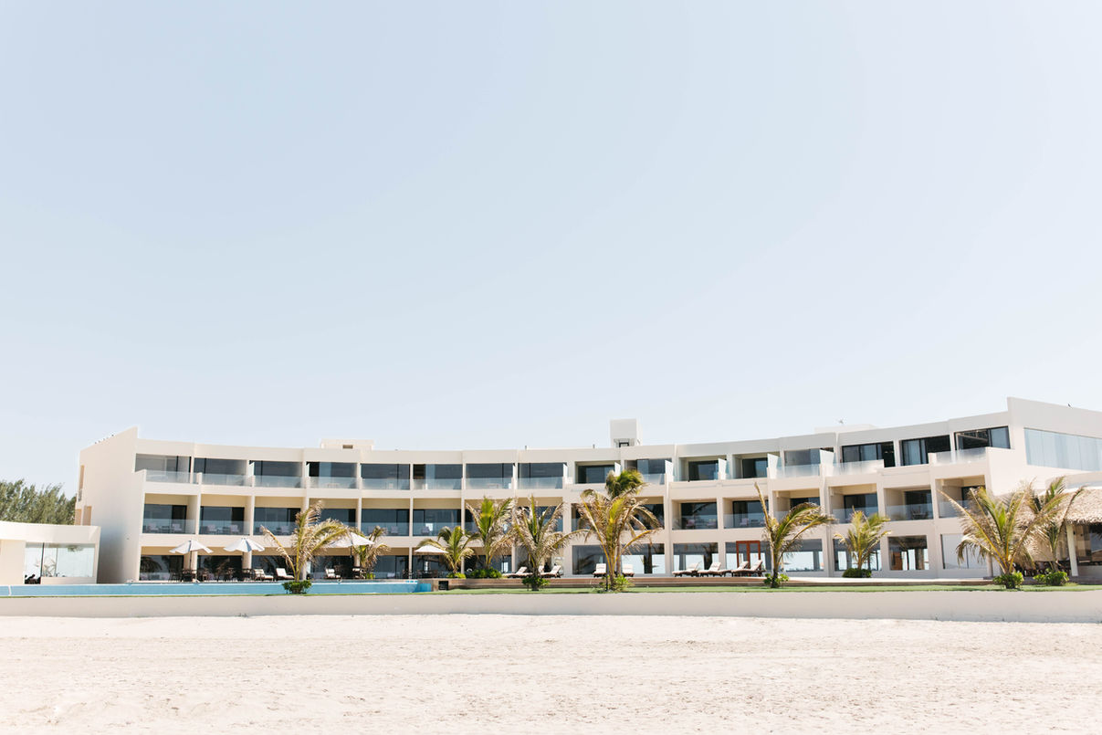Un gran edificio blanco está situado encima de una playa de arena.