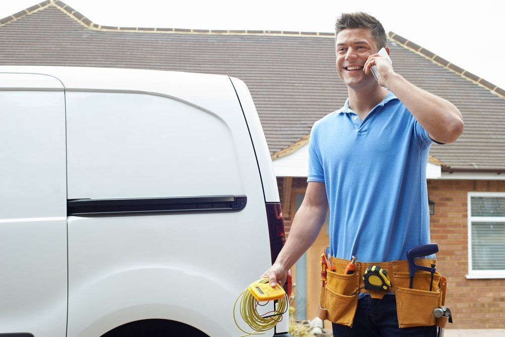 Man With Tool Belt Talks on Phone Near a White Van — Big Electrics in Redlynch, QLD