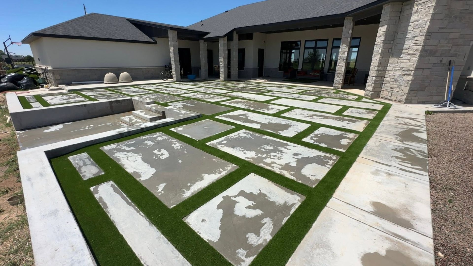 A small green putting green with two flagsticks, surrounded by gravel and desert landscape.