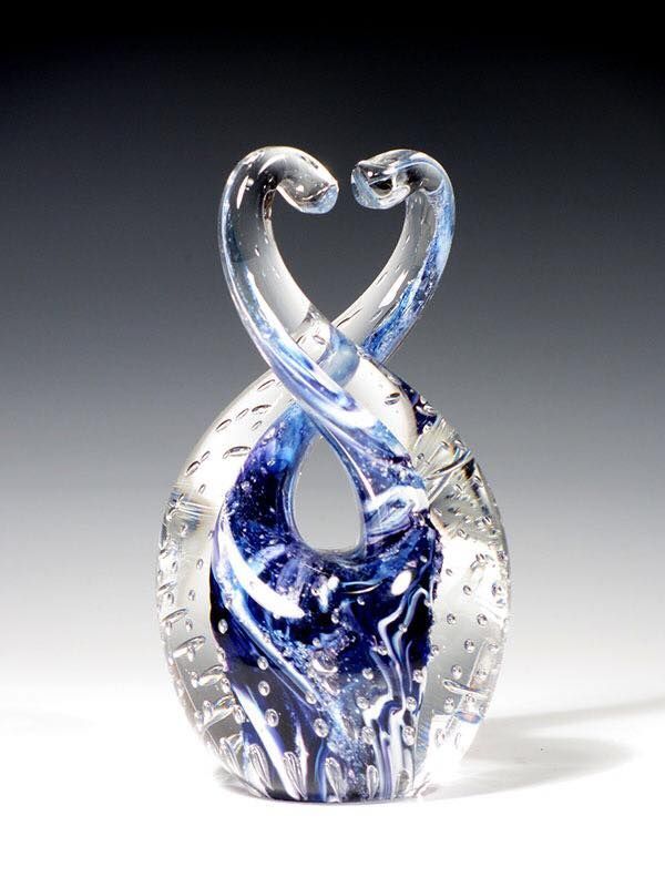 Glass sculpture of two intertwined blue and clear ribbons, suggesting a heart shape.