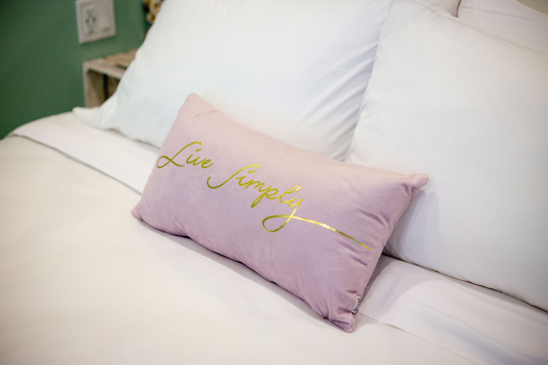 White bed with pillows, one lavender pillow with