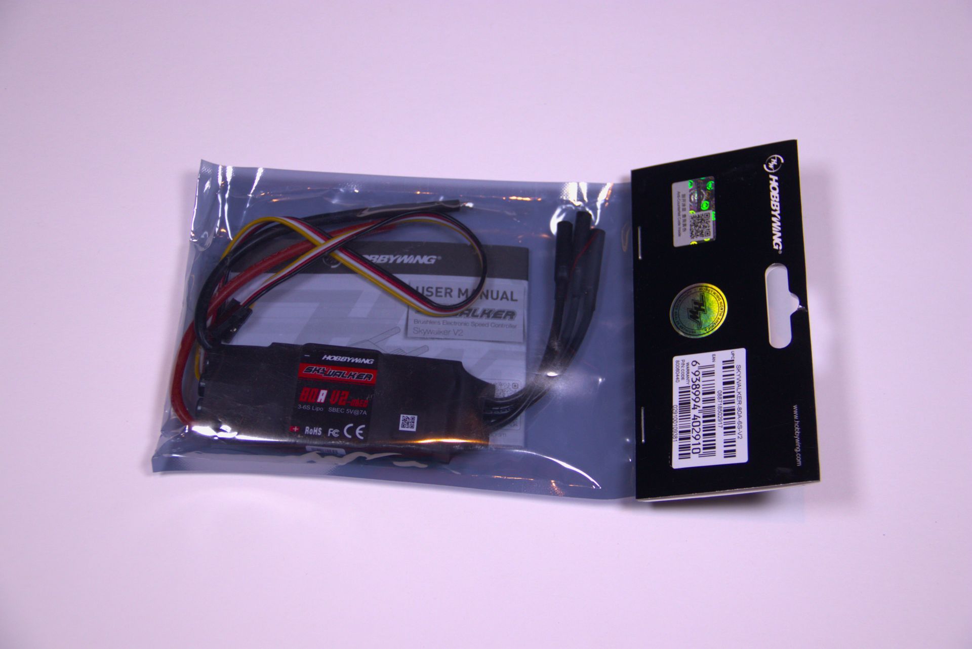 Plastic bag with a black electronic cable and small red-and-black components on a light surface