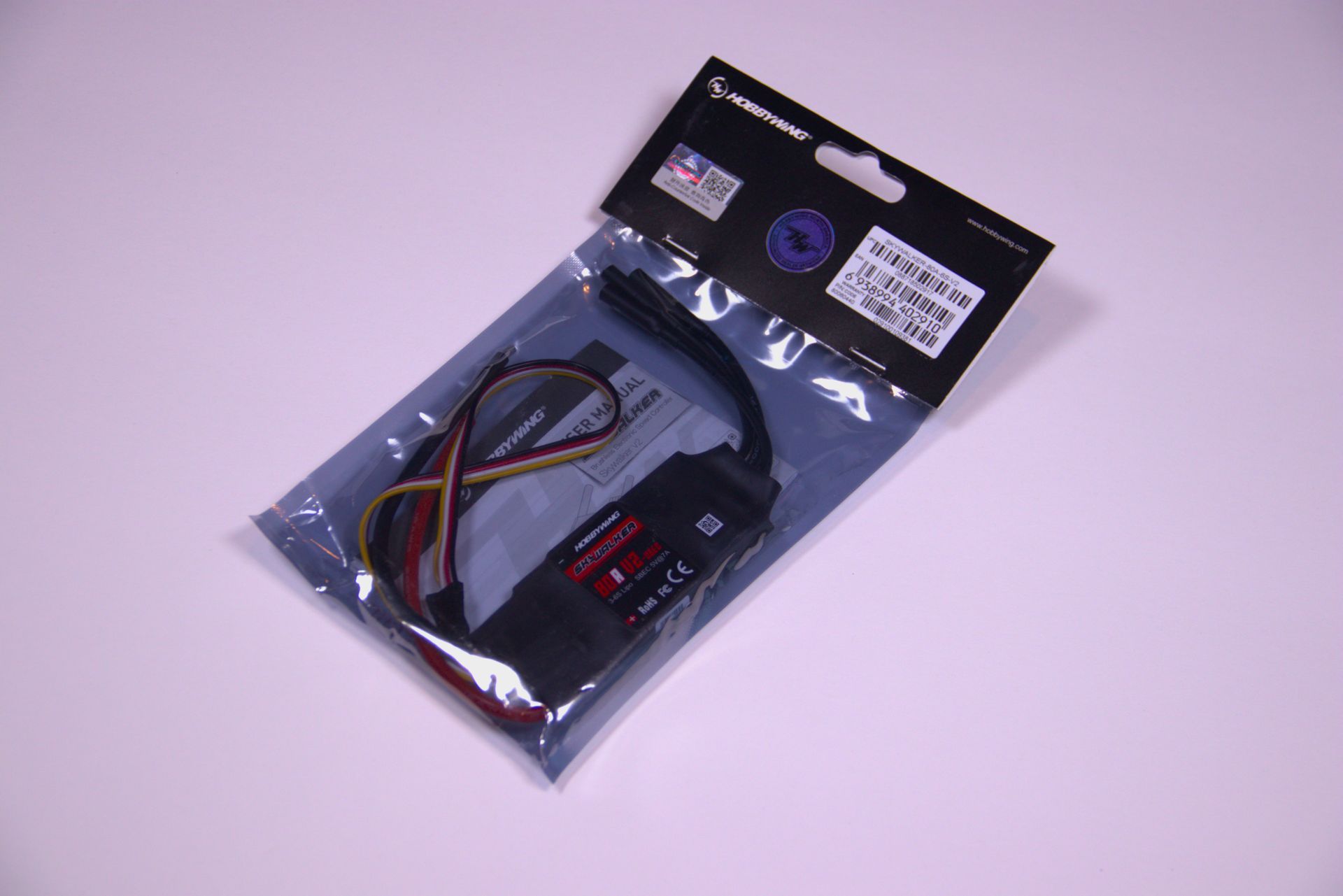 Plastic bag with a black electronic cable and small red-and-black components on a light surface