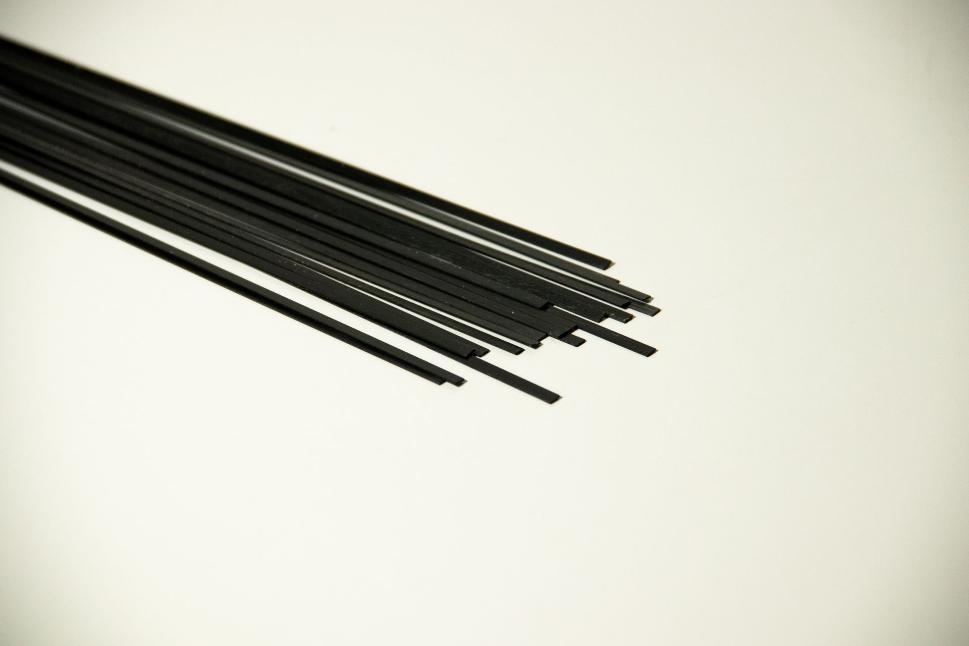 Several thin black rods or cables fanned out on a light background