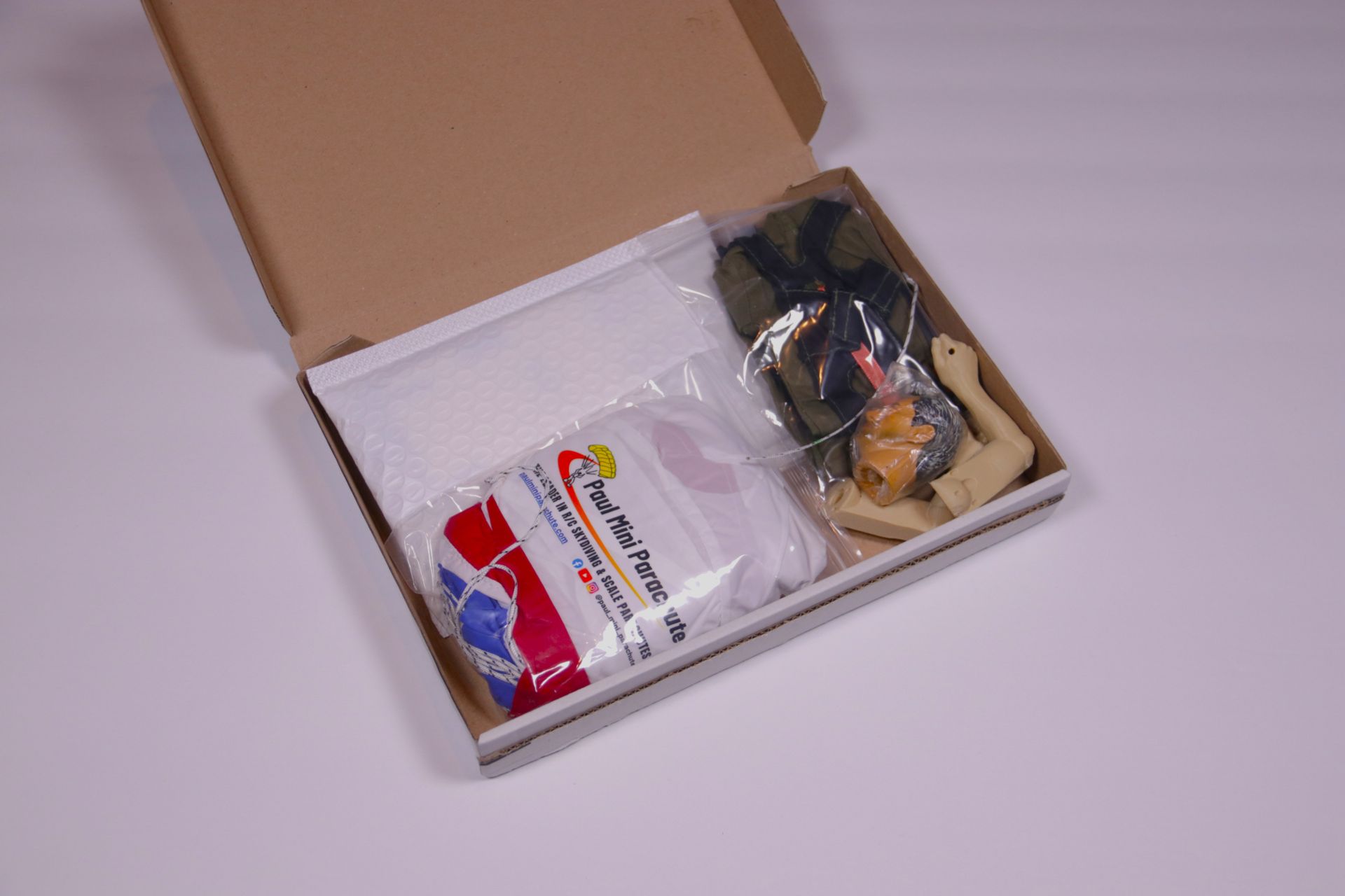 Open cardboard box with packaged items, including a white bag and small parts inside.