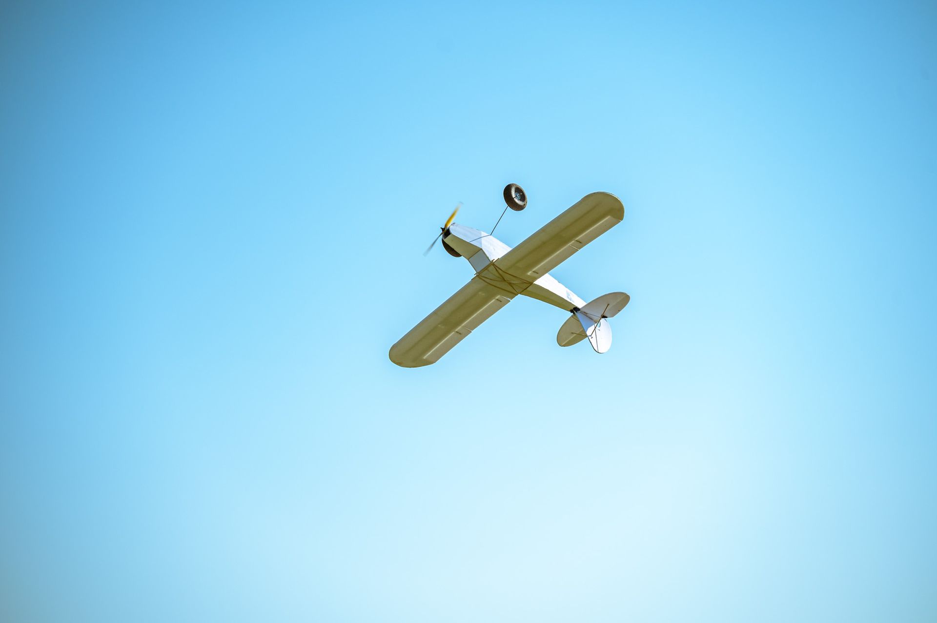 Small yellow biplane flying against a clear blue sky