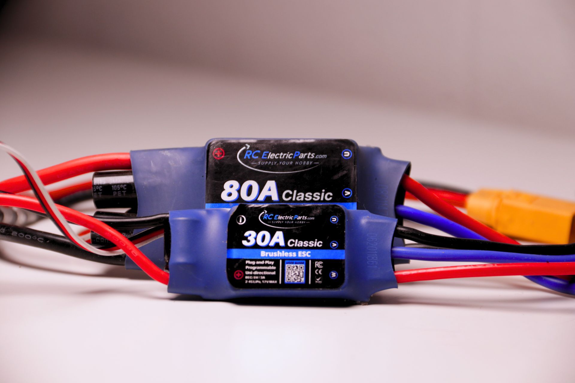 Two blue electronic speed controllers with labels, wires, and connectors. The top is 80A, the bottom is 30A.