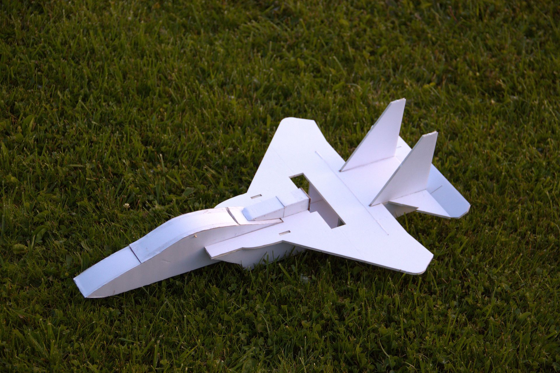 White model jet plane resting on green grass outdoors
