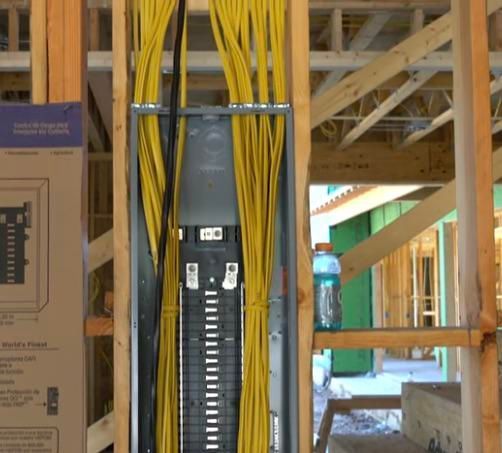 Electrical panel with yellow wiring inside a construction site wall frame