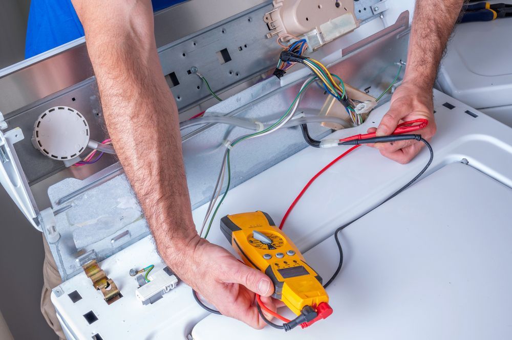 Technician testing appliance wiring with a multimeter inside a dishwasher panel