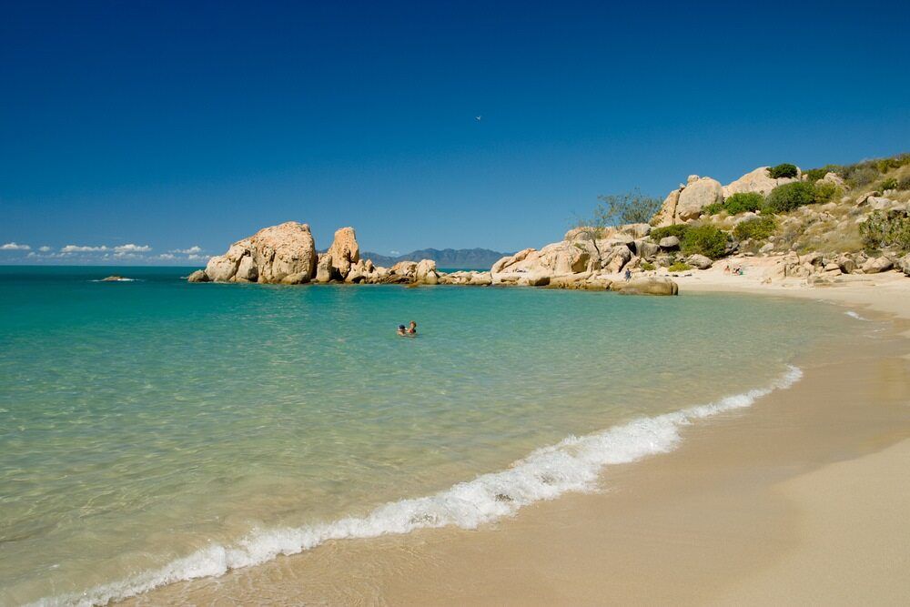 A Couple Of People Are Swimming In The Ocean On A Beach — SureLift Crane Hire In Bowen, QLD
