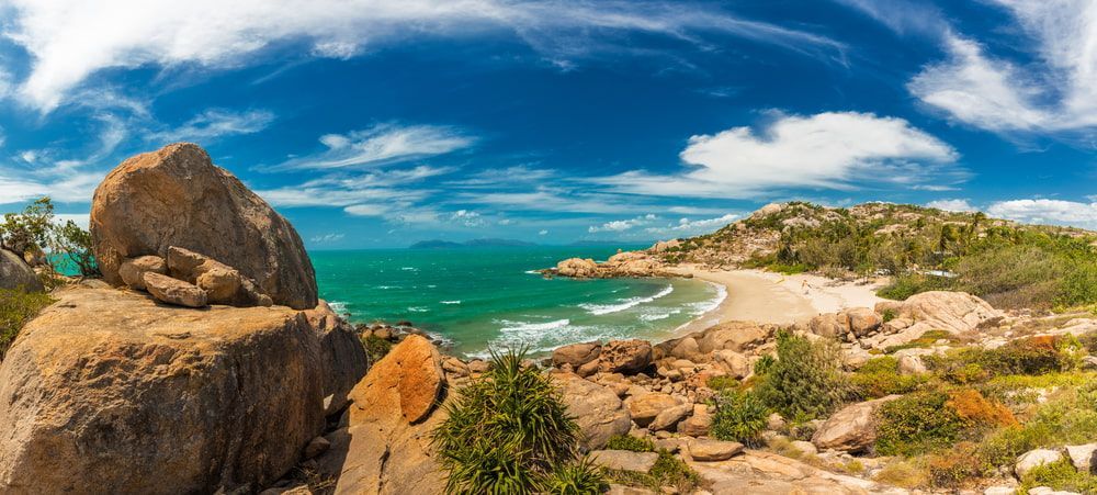 A Large Rock Is Sitting On Top Of A Hill Next To A Beach — SureLift Crane Hire In Bowen, QLD