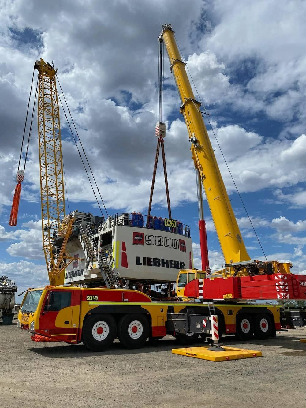 A Yellow And Red Liebherr Truck Is Being Lifted By A Large Crane — SureLift Crane Hire In Mackay, QLD