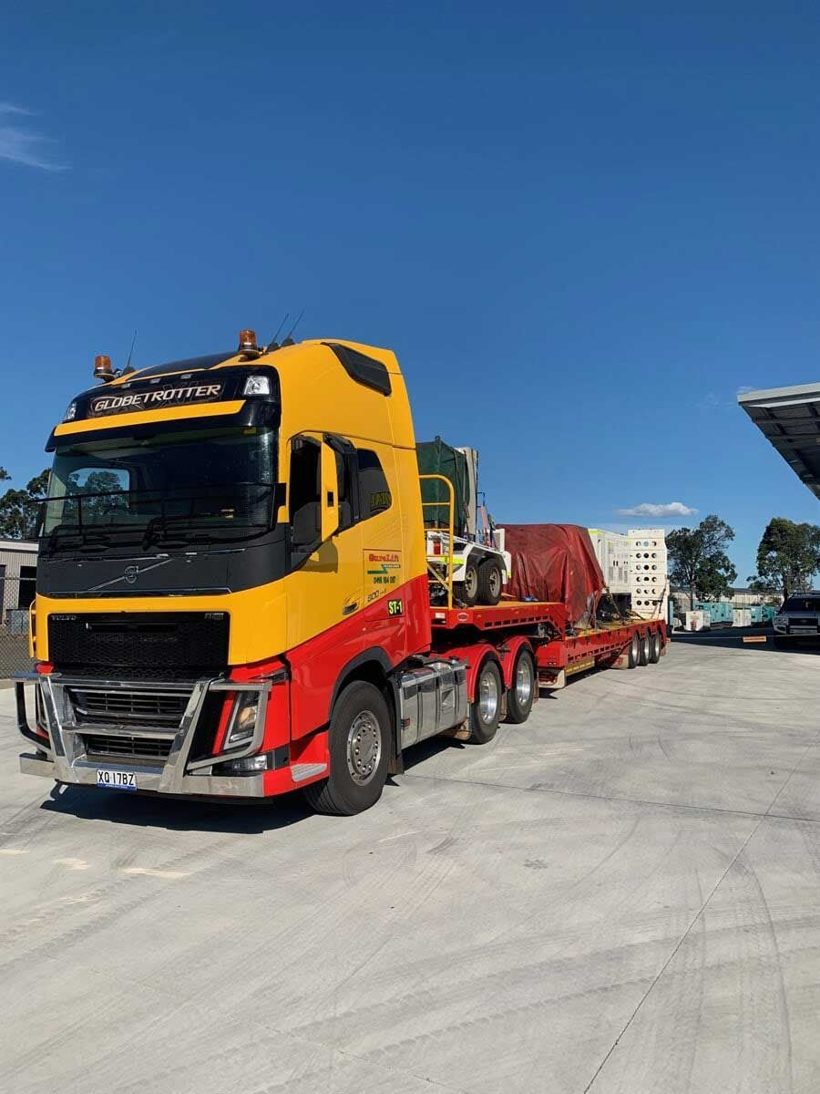 A Yellow And Red Semi Truck Is Parked In A Parking Lot — Surelift Crane Hire In Bowen, QLD