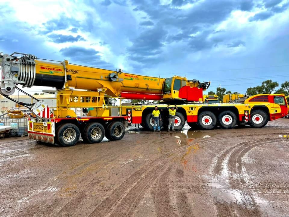 A Large Yellow And Red Crane Is Parked On A Dirt Road — SureLift Crane Hire In Moranbah, QLD