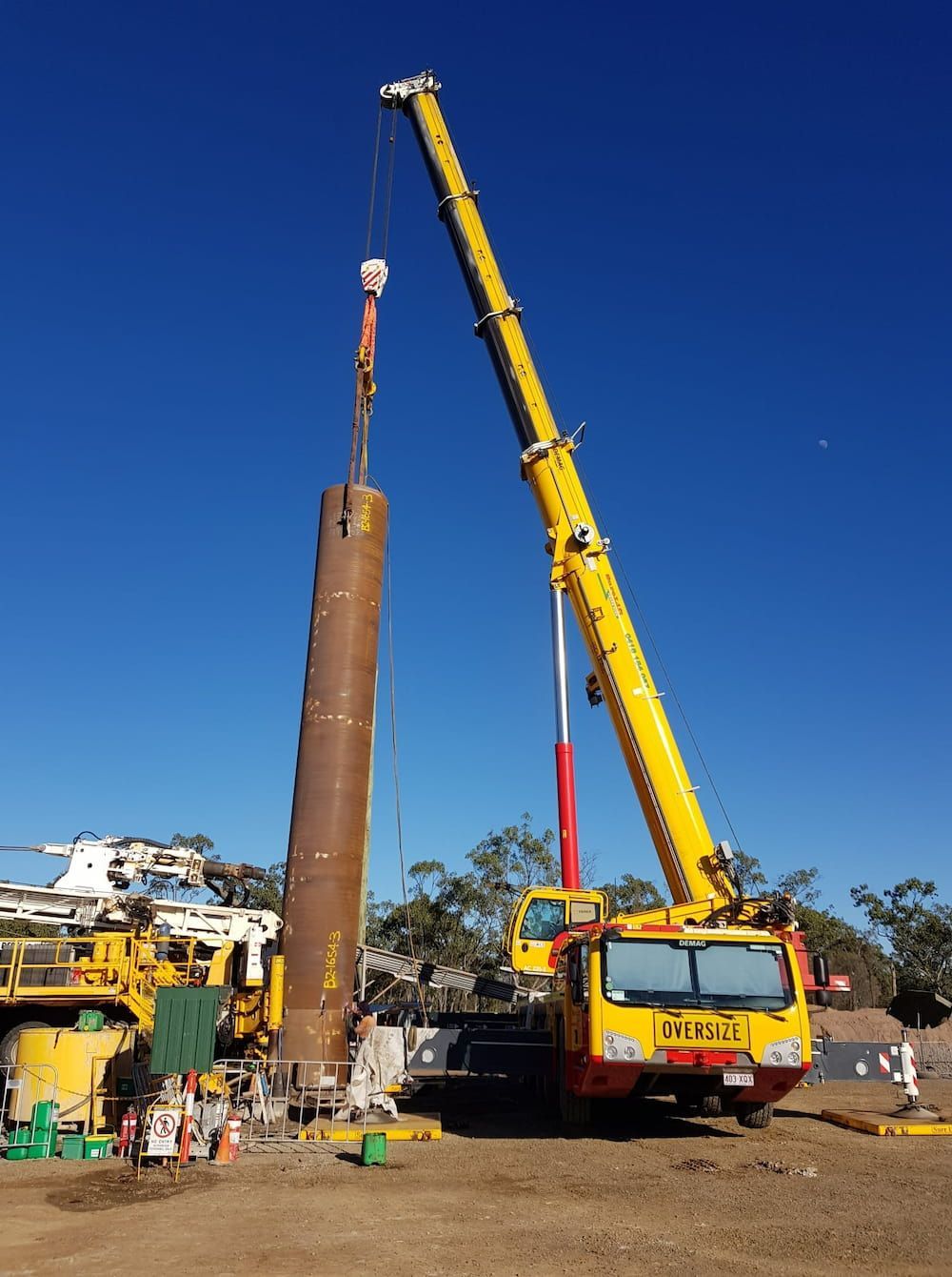 A Large Yellow Crane Is Lifting A Large Pipe — SureLift Crane Hire In Emerald, QLD