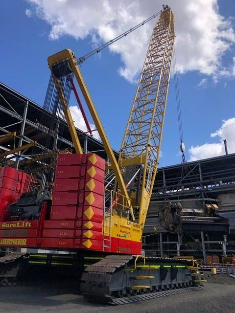 A Red And Yellow Crane Is Parked In Front Of A Building — Surelift Crane Hire In Bowen, QLD