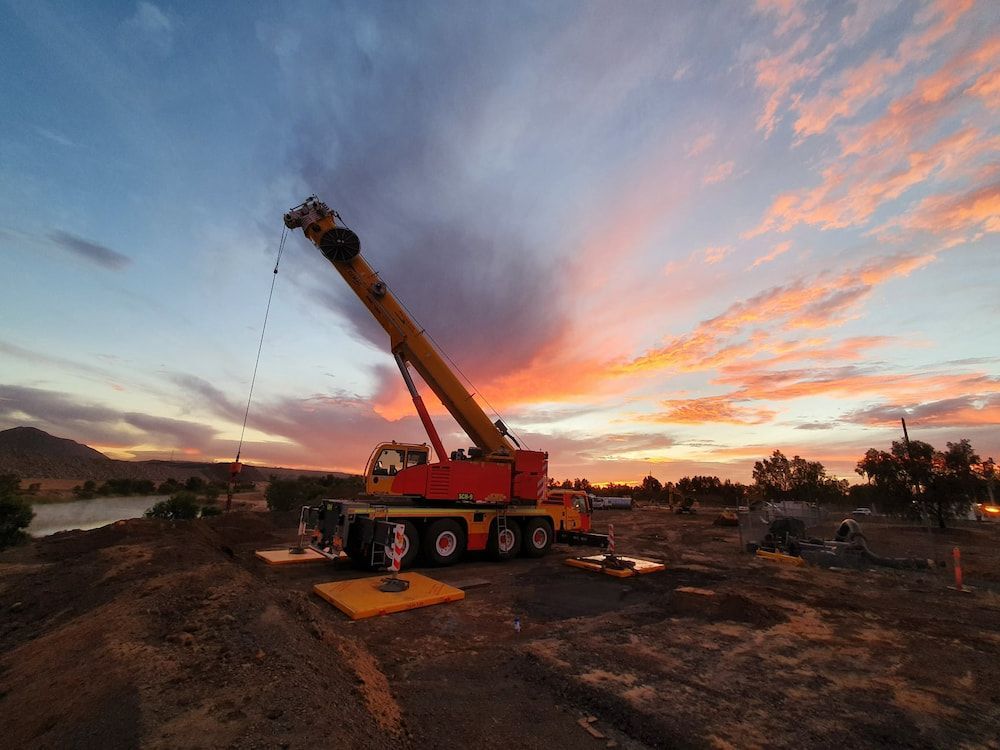 A Large Crane Is Sitting On Top Of A Dirt Hill At Sunset — SureLift Crane Hire In Moranbah, QLD