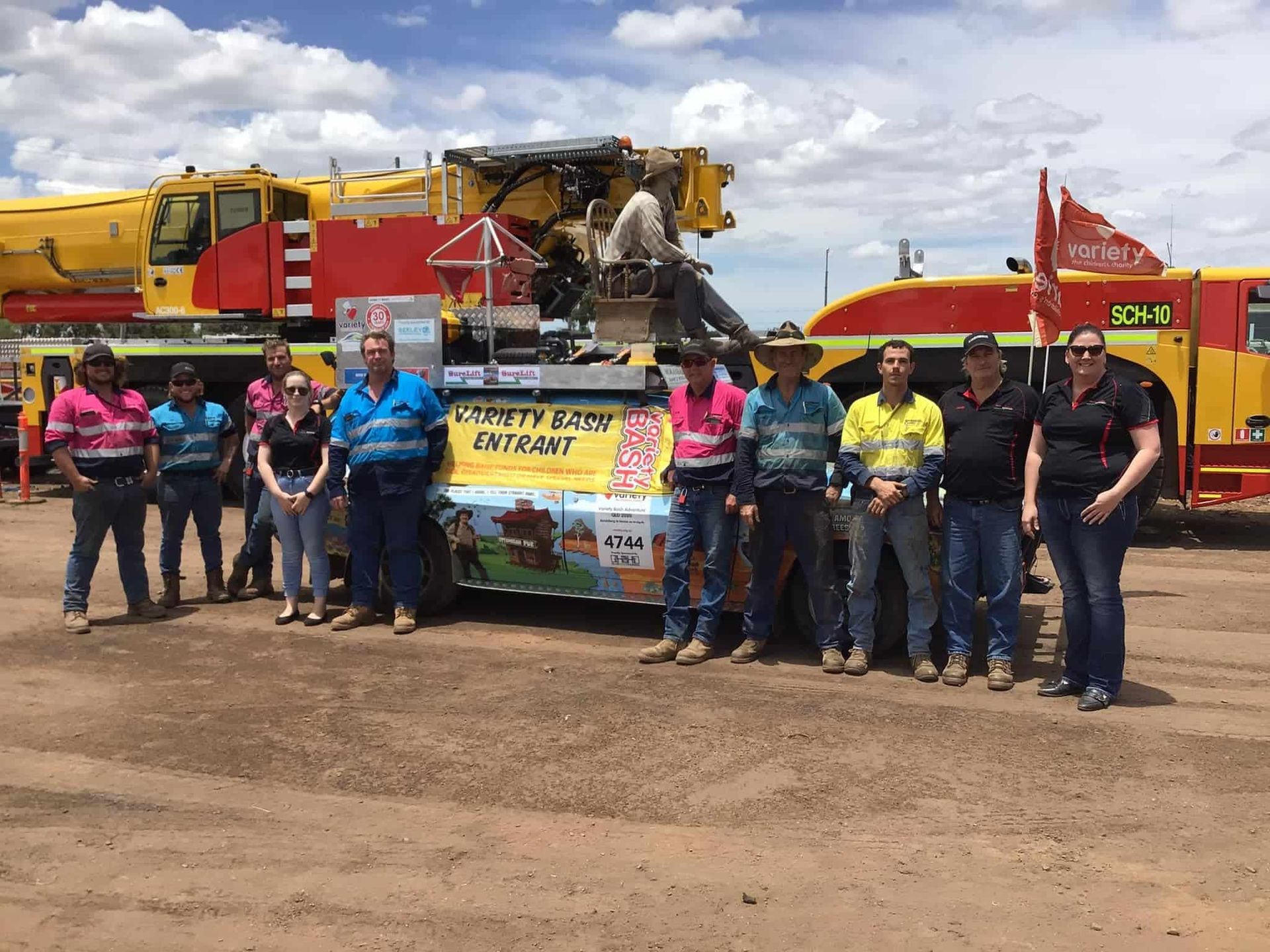 A Group Of People Are Posing For A Picture In Front Of A Truck That Says Caterpillar — SureLift Crane Hire In Moranbah, QLD