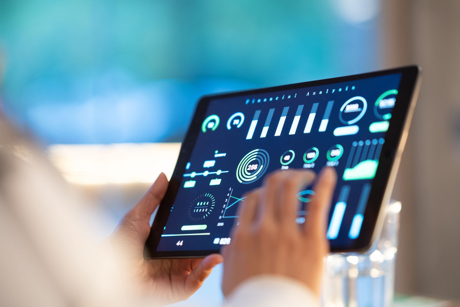 Person using tablet displaying financial analytics, with hand touching the screen.