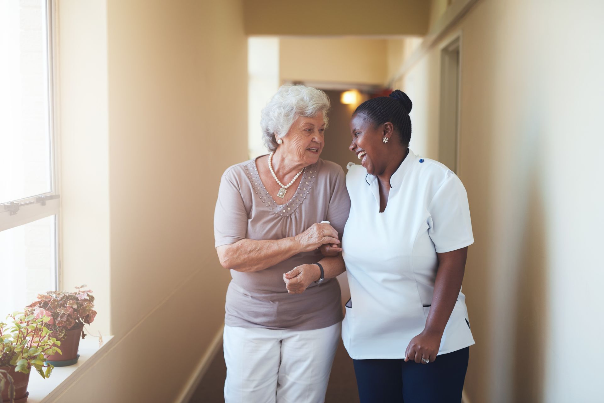 Nurse kneels beside an elderly person in a rocking chair, holding a cane and conversing indoors Nurse kneels beside an elderly person in a rocking chair, holding a cane and conversing indoors