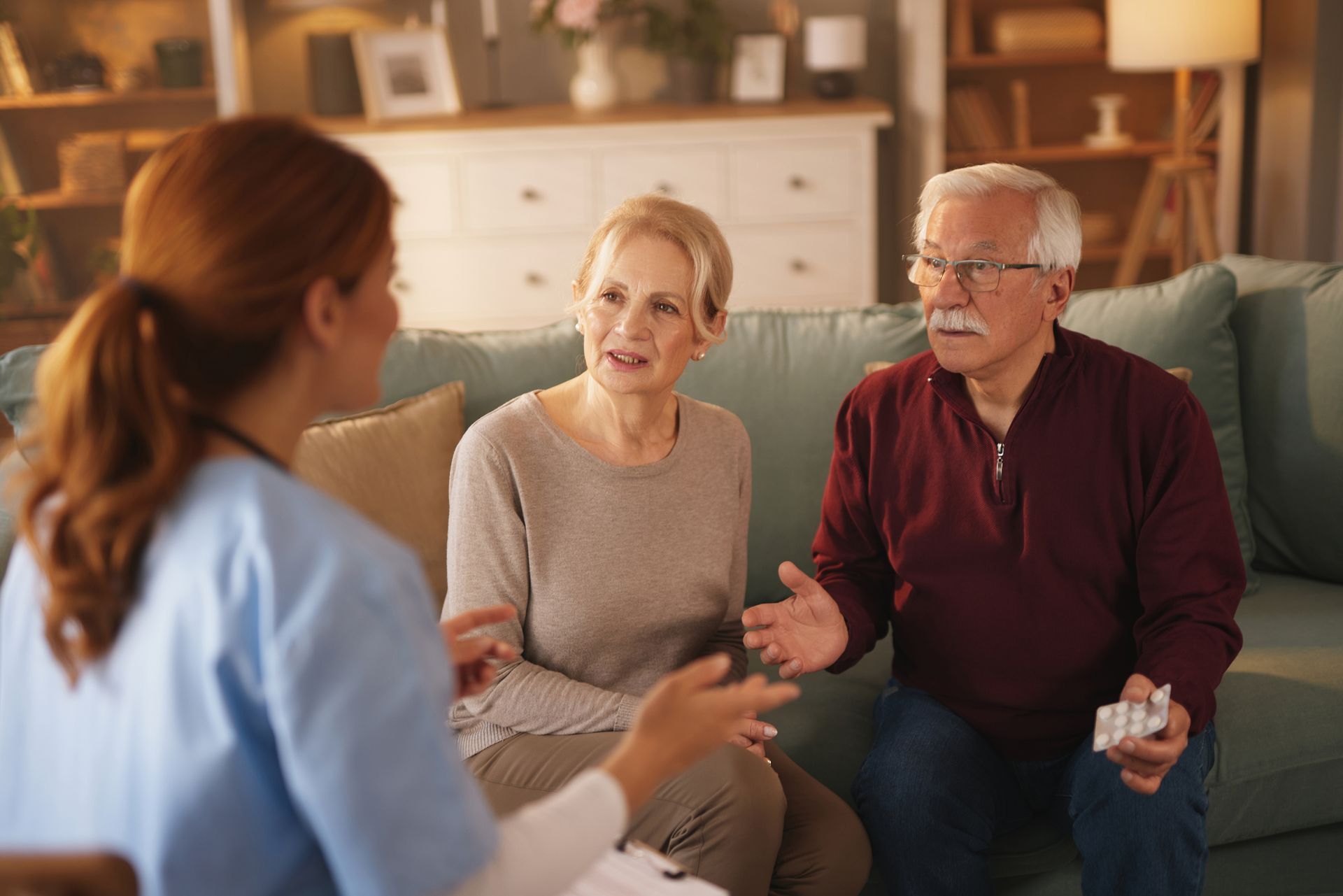 Nurse consulting with senior couple on a sofa, discussing medication. Nurse consulting with senior couple on a sofa, discussing medication.