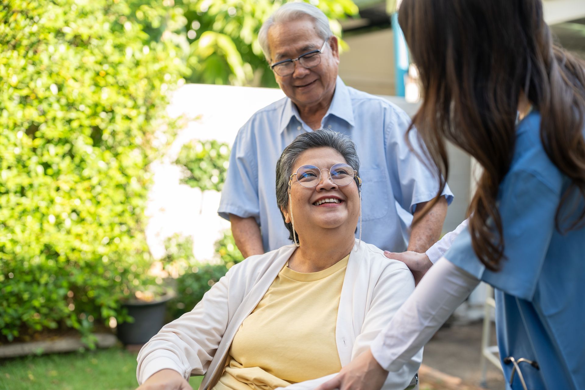 A healthcare worker in blue scrubs taking an older person's blood pressure, indoors