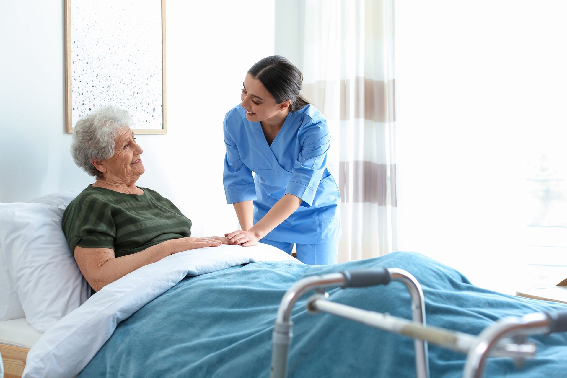 Nurse tending to an elderly person in bed with a walker nearby